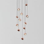 Cluster of Clérachic globe pendants with rose gold caps and clear lower halves hanging at varied heights on a pale grey backdrop.