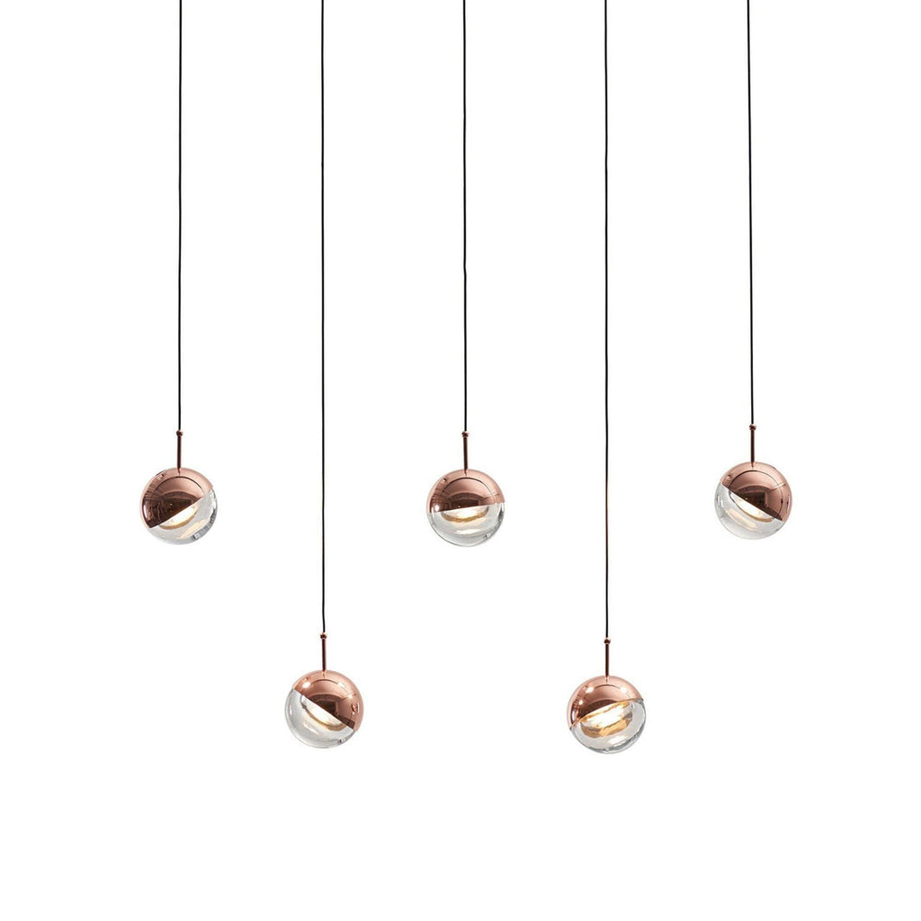Five rose gold Clérachic globe pendants hung at staggered heights on a pale backdrop, each with a clear glass lower half.