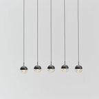Five Clérachic globe pendants with matt black caps and clear lower halves, hung in a row on thin cords against a pale grey backdrop.