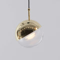 Close view of a gold-finish Clérachic globe pendant, its mirror-polished half-cap over a clear glass half with a lit LED.