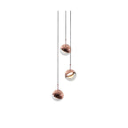 Three rose gold Clérachic globe pendants at different heights on thin cords, on a plain white backdrop.