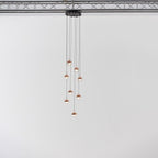 Narrow cluster of small rose gold Clérachic globe pendants on cords of varied length, hung from a black ceiling plate.