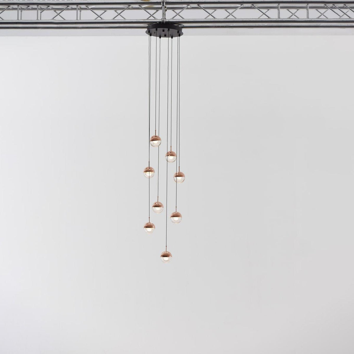 Narrow cluster of small rose gold Clérachic globe pendants on cords of varied length, hung from a black ceiling plate.