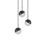 Three matt black Clérachic globe pendants with clear lower halves, hung at staggered heights on a white backdrop.