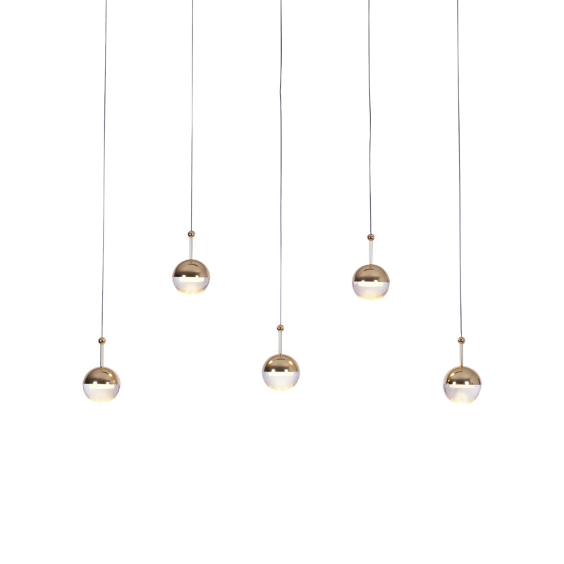 Five small gold-toned Clérachic globe pendants hung at staggered heights on long thin cords, on a white backdrop.