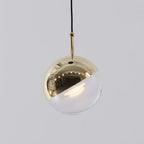 Close view of a pale gold-finish Clérachic globe pendant, its mirror-polished half-cap over a clear glass half.