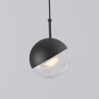 Close view of a matt black Clérachic globe pendant with a short black stem and a clear glass lower half.