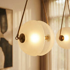 Clérachic close-up of a frosted glass half-disc pendant glowing warm, with a brass cap and thin brass frame arms.