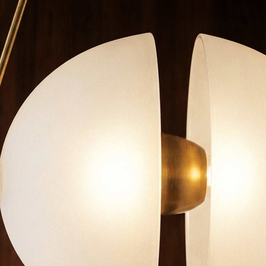Clérachic tight view of two frosted glass half-discs with a brushed brass centre, lit warm against dark wood.