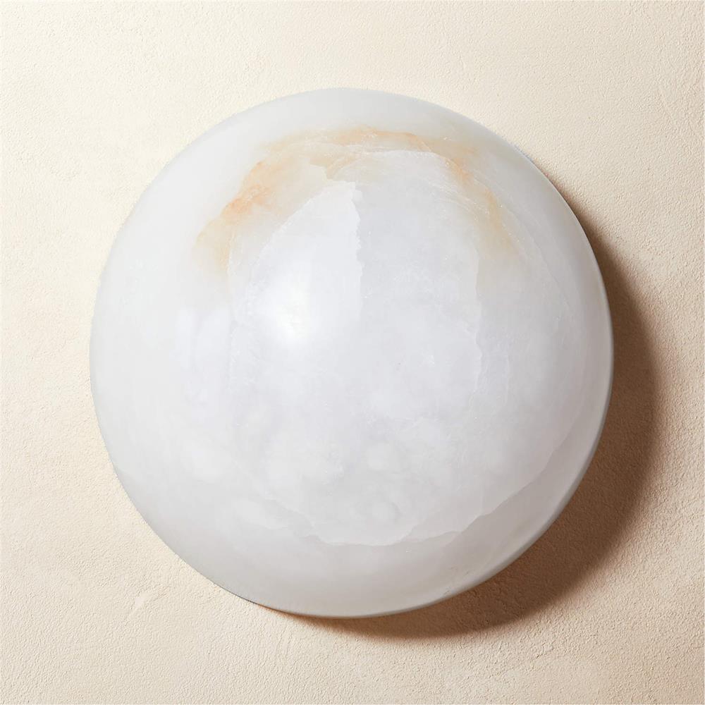 The Half-Dome Alabaster Wall Sconce from Clérachic unlit up close, amber veining drifting across the top of the pale stone dome.