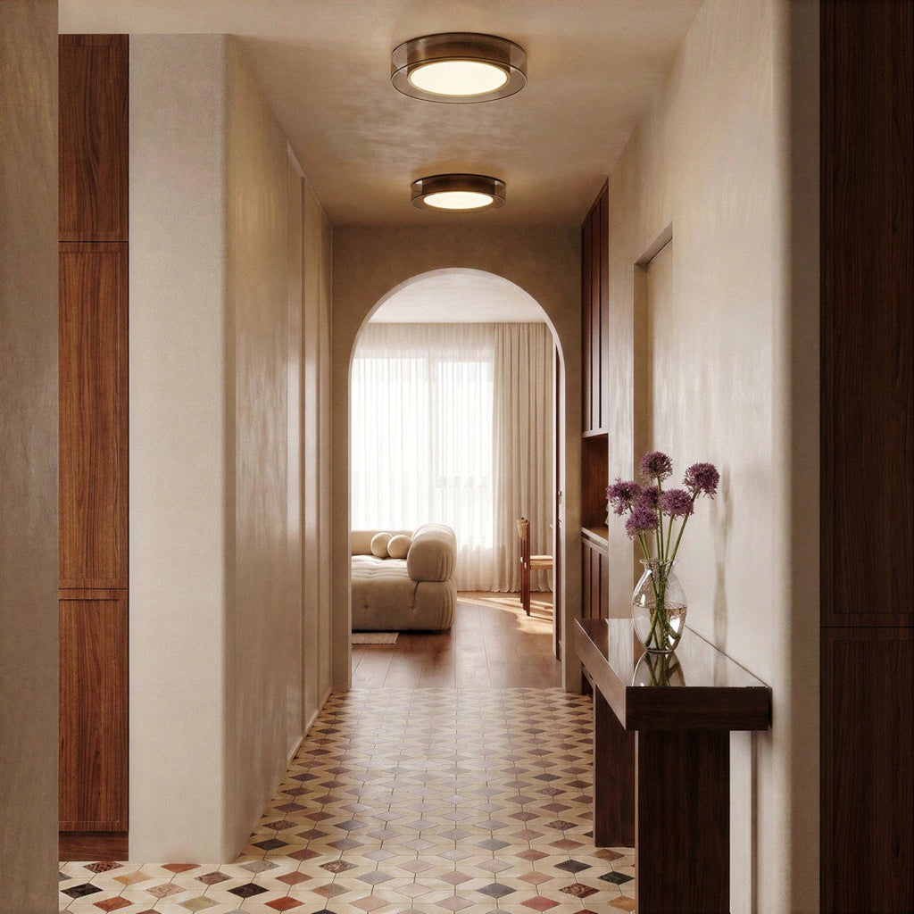 Two Clérachic halo ring ceiling lights glow along a tiled hallway leading through an arch to a sunlit living room.