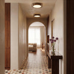 Two Clérachic halo ring ceiling lights glow along a tiled hallway leading through an arch to a sunlit living room.