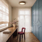 Clérachic halo ring ceiling light glowing above a desk nook with sheer curtains and a blue paneled wardrobe.