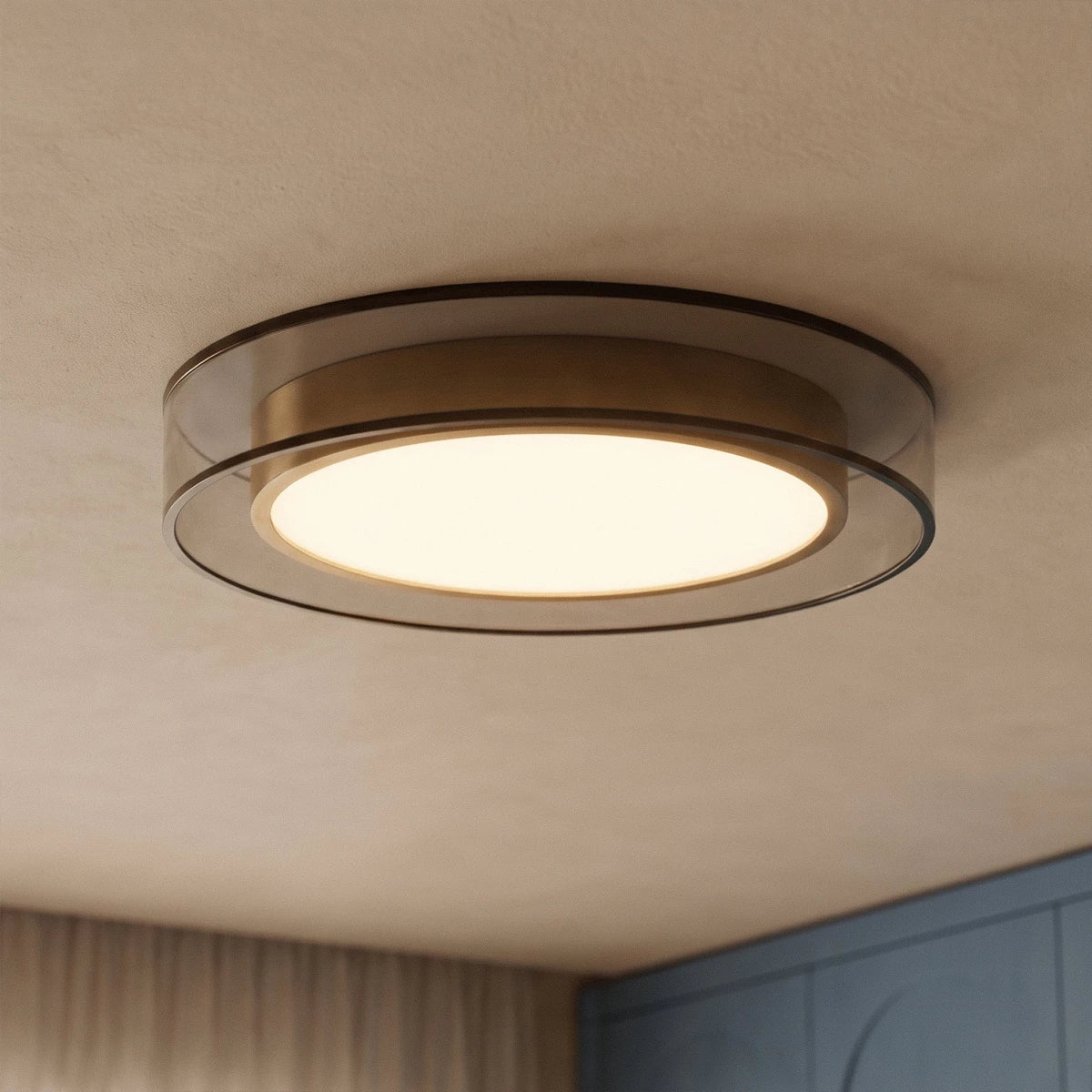 Close view of the Clérachic halo ring ceiling light glowing near a blue paneled wardrobe and sheer curtained window.
