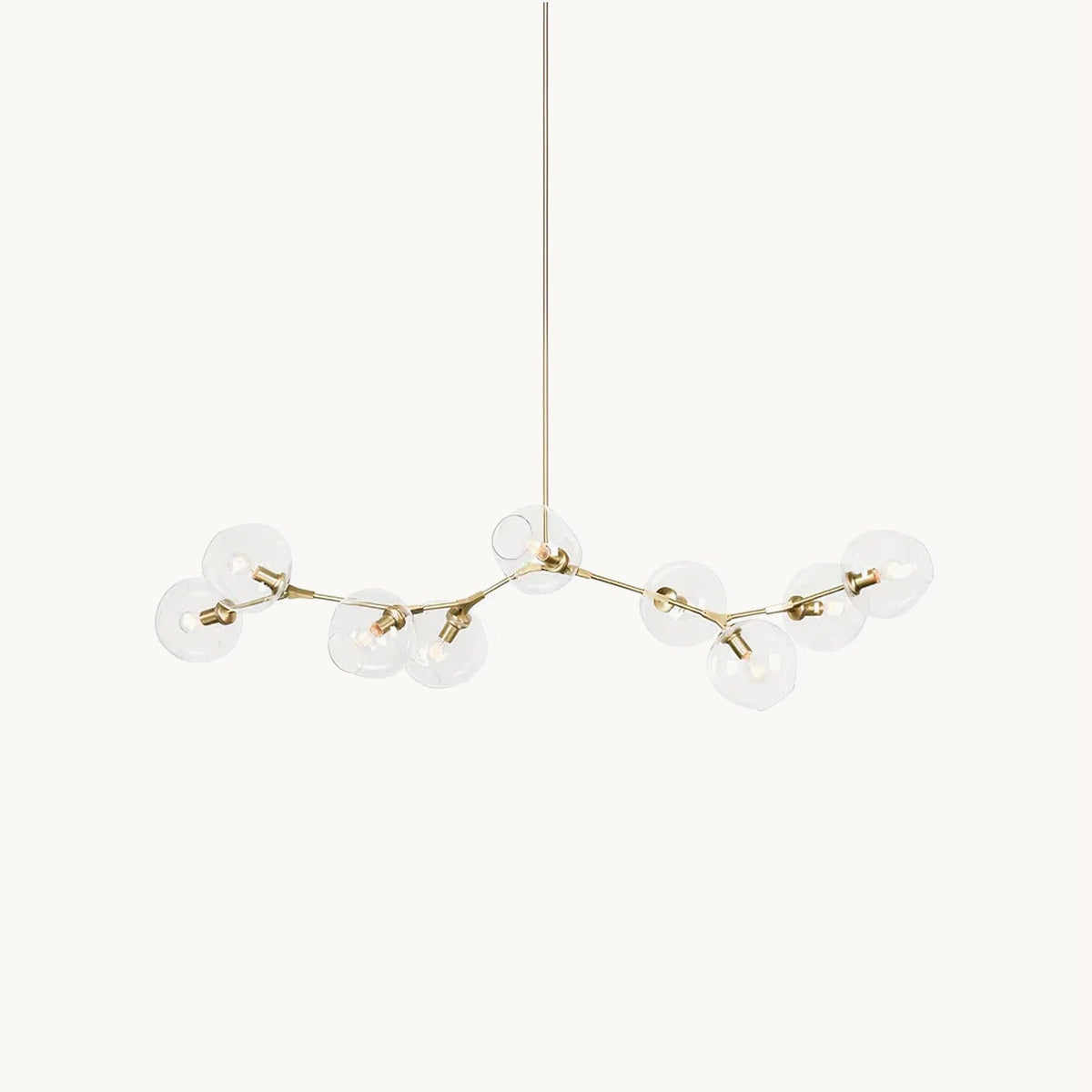 A Clérachic chandelier on a plain white backdrop, with clear glass globes on slim gold arms branching from a long central rod.