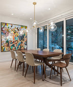 This Clérachic chandelier hangs over a walnut dining table, its clear glass globes reflecting a bright painting on the wall.