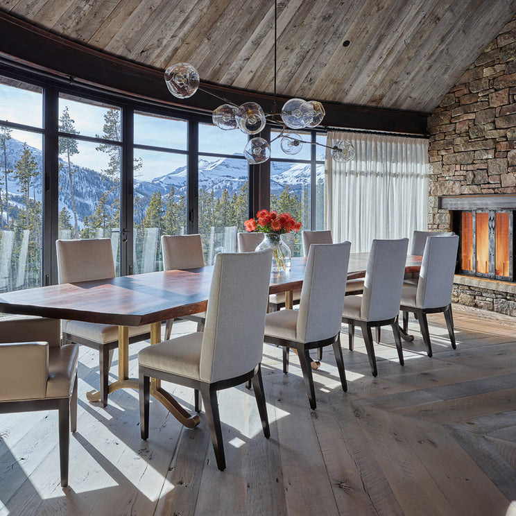 This Clérachic chandelier floats beneath a reclaimed-wood ceiling above a long dining table, with snowy mountain views behind.