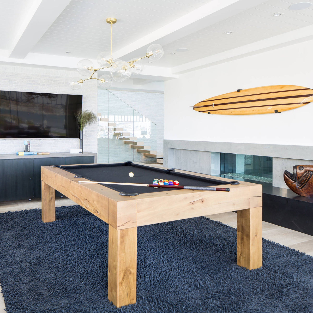 This Clérachic chandelier in gold and clear glass hangs in a bright games room above a pool table and a navy shag rug.
