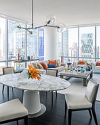 This Clérachic chandelier in black and clear glass hangs over an oval marble dining table, with city towers visible through the glass wall.