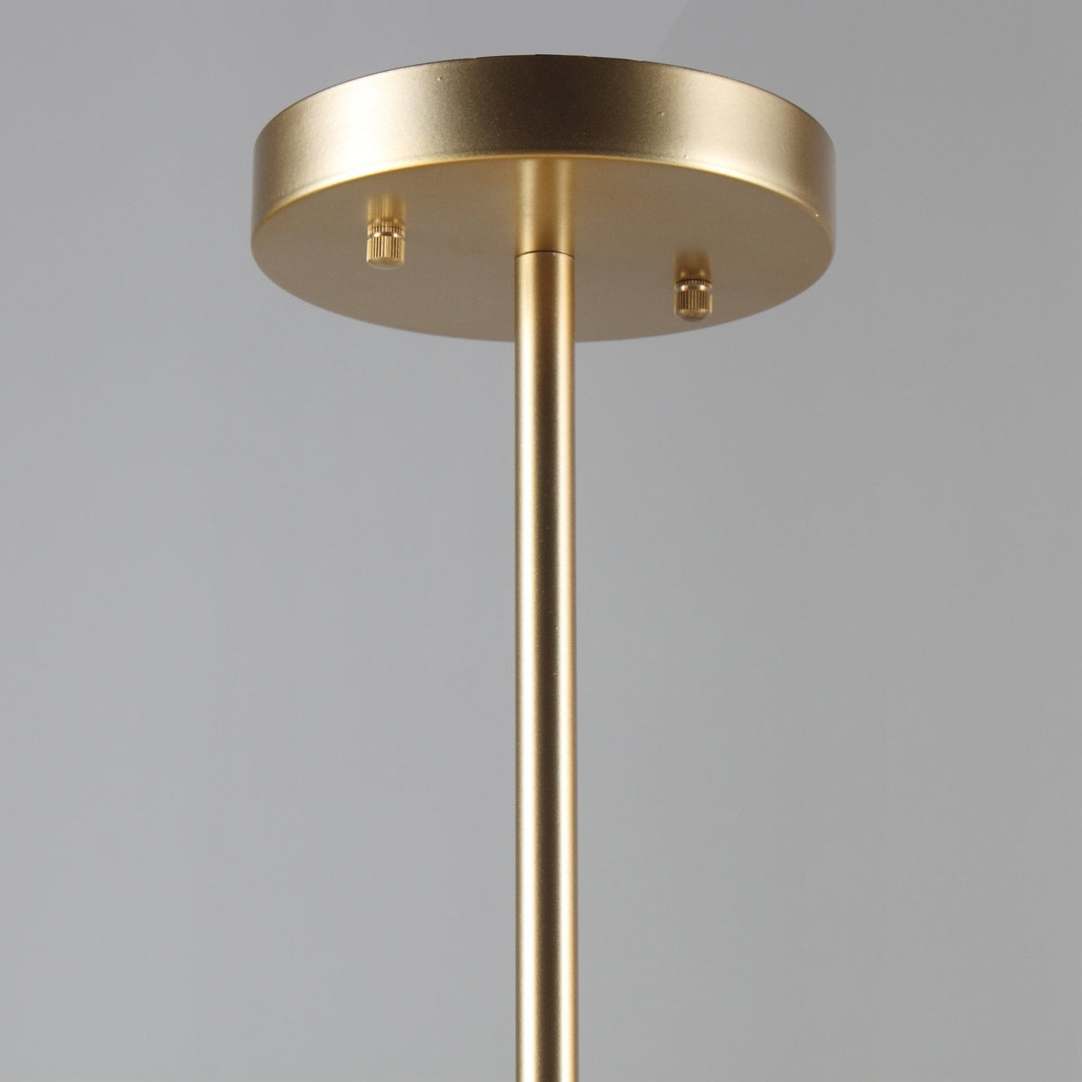 Close view of the round gold ceiling plate and slim gold rod that carry this Clérachic chandelier.