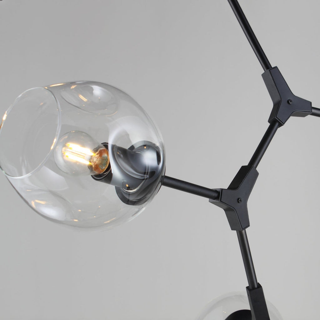 Close view of a dimpled clear glass globe on a black arm and Y-shaped joint of this Clérachic chandelier.
