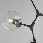 Close view of a dimpled clear glass globe on a black arm and Y-shaped joint of this Clérachic chandelier.