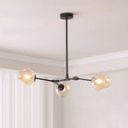 Black-framed Clérachic chandelier with three amber glass globes hanging from a short rod in a pale room with white curtains.
