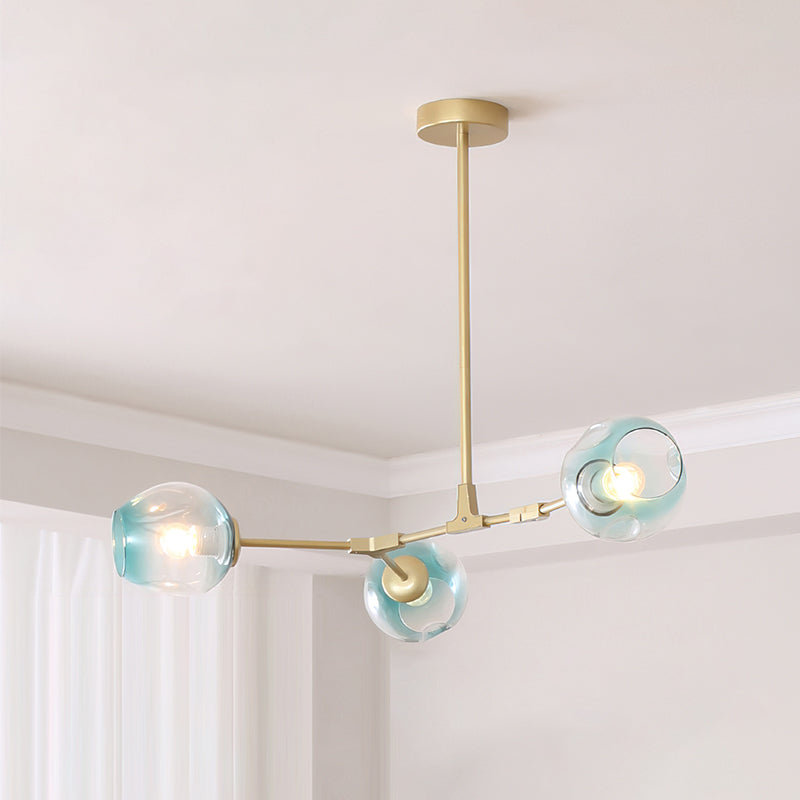 Gold Clérachic chandelier with three gradient blue glass globes on short arms, hung from a rod below a pale ceiling and curtains.