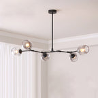 Black Clérachic chandelier with five gradient grey glass globes on slim arms, hung in a corner beside white curtains.