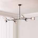 Black Clérachic chandelier with seven gradient grey glass globes spread across a pale ceiling beside white curtains.