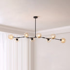 Black Clérachic chandelier with eight amber glass globes lit along a long branching frame, hung in a room with white curtains.
