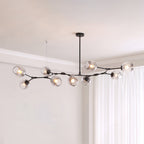 Long black Clérachic chandelier with nine gradient grey glass globes along a branching frame, below a pale corner ceiling.