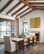 Clérachic chandelier with clear globes in a dining room with exposed timber roof beams, a limestone table and a fireplace.
