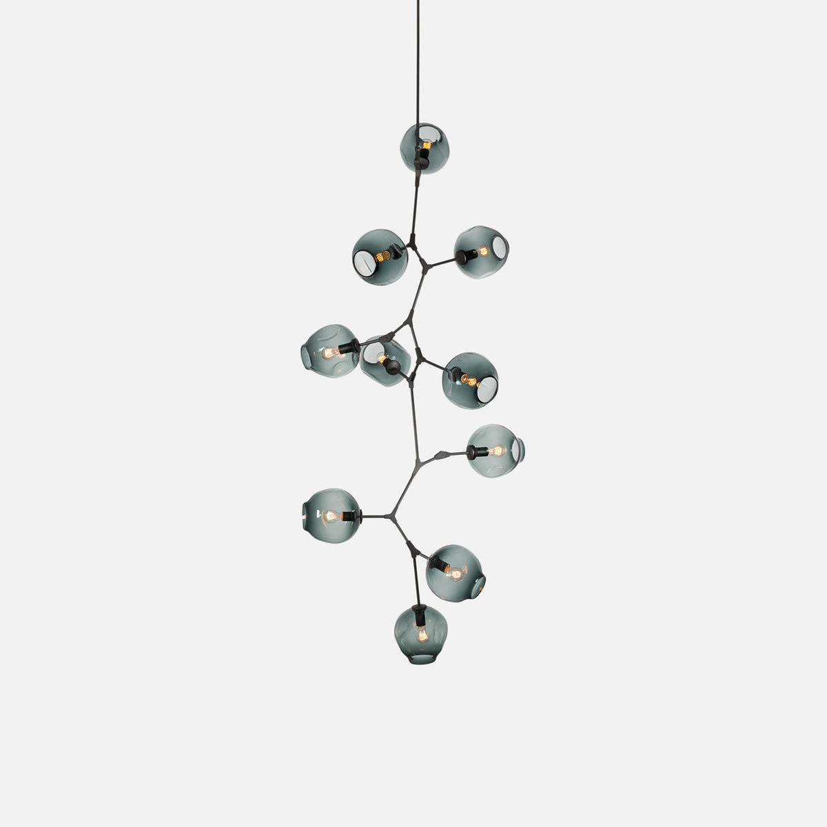Black-framed Clérachic chandelier on a pale grey backdrop, with smoky blue-grey globes stepping down a branching frame.