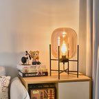 Warm orange-amber glass glows around the bulb in this Clérachic table lamp, standing on a wooden shelf unit with books.