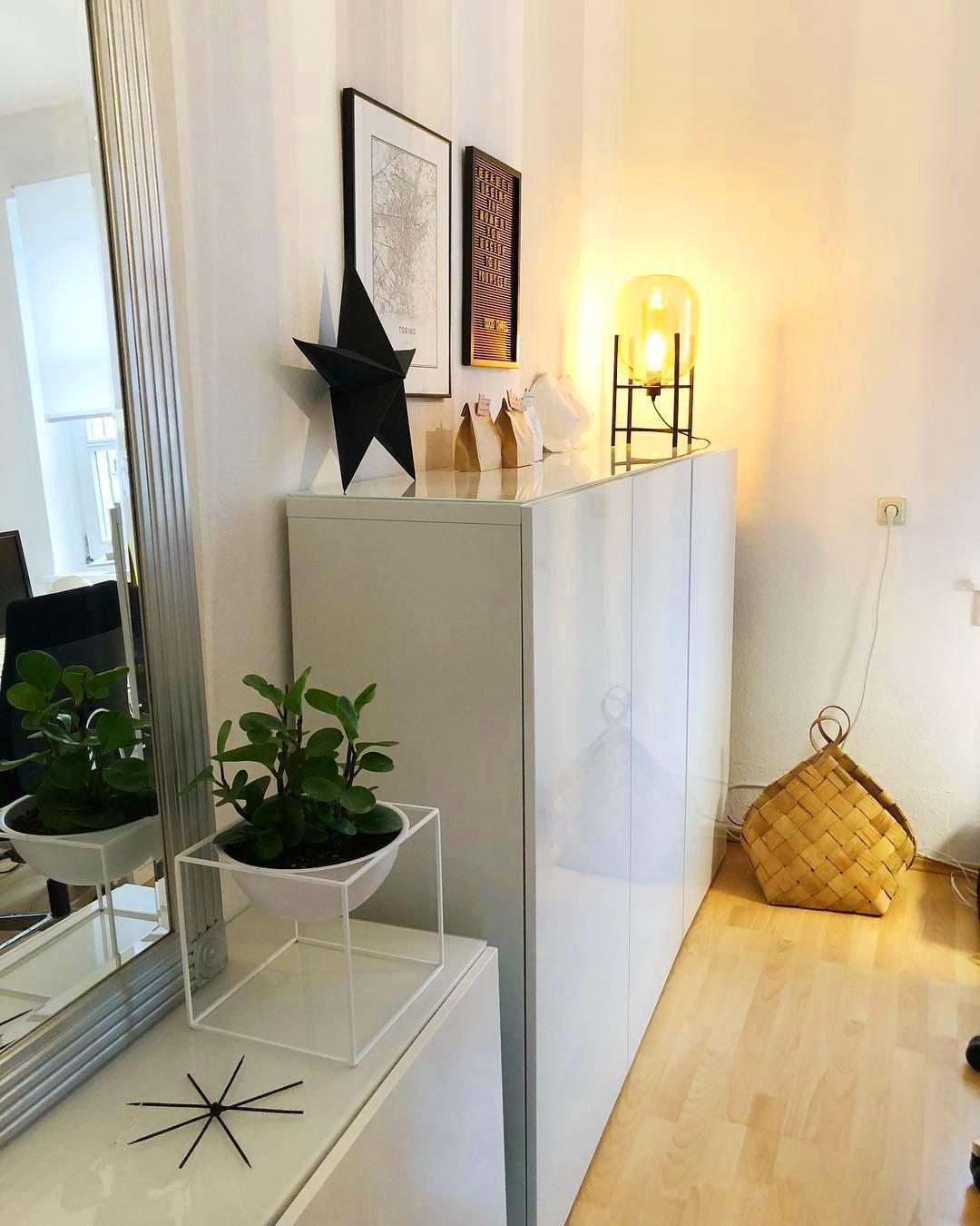 Warm light from this Clérachic table lamp lifts the corner of a sideboard, next to a black star ornament in a white hallway.