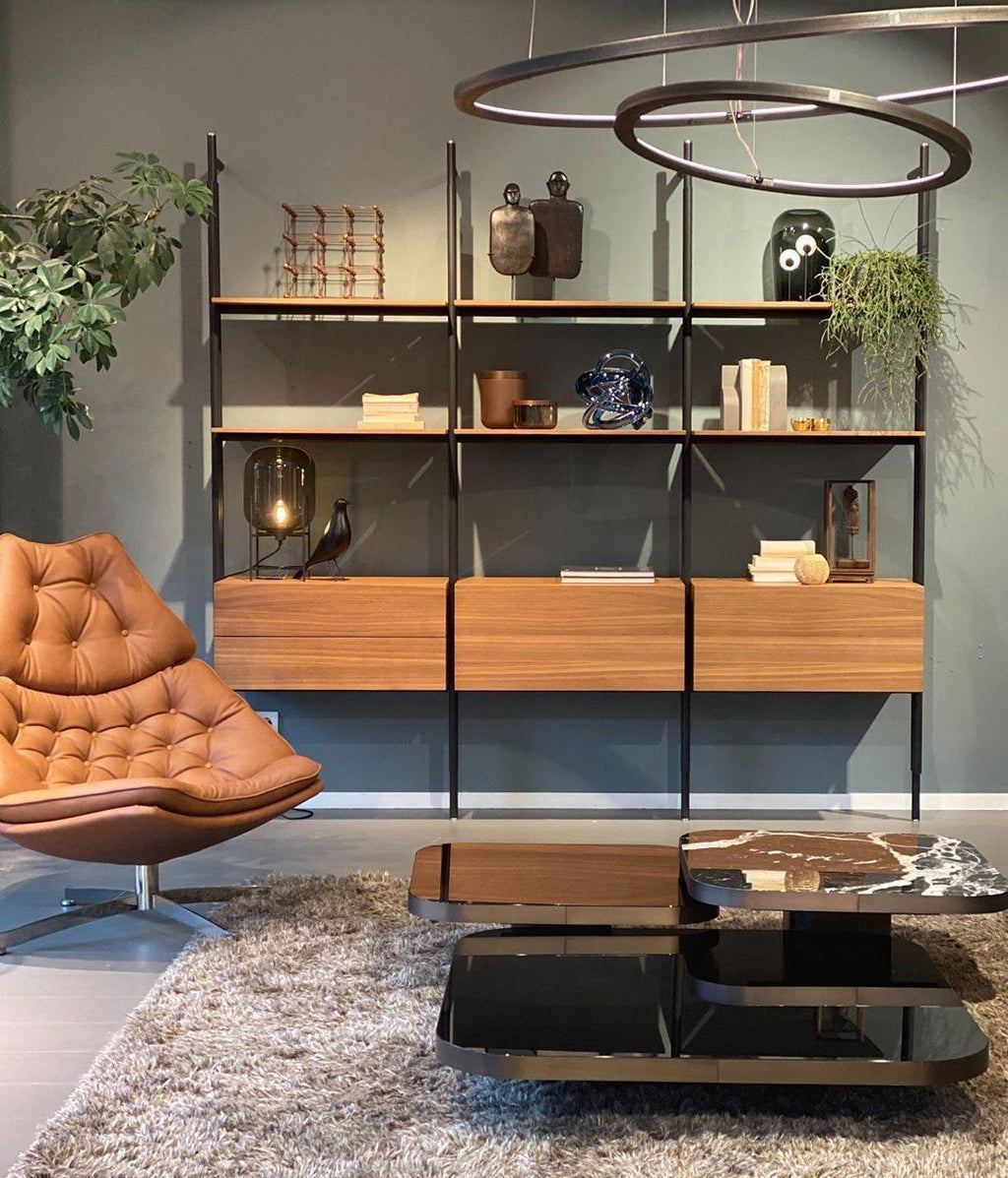 Small Clérachic glass lamp on a shelf unit in a grey-green living room, with an orange leather chair and a low marble table.