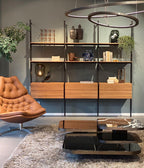 Small Clérachic glass lamp on a shelf unit in a grey-green living room, with an orange leather chair and a low marble table.
