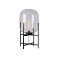 Clear glass shade with a long filament bulb on a black four-leg frame, shown on a plain white background for this Clérachic lamp.