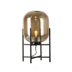 Light brown-amber glass shade with a lit filament bulb on a black frame, shown on a white backdrop for this Clérachic lamp.