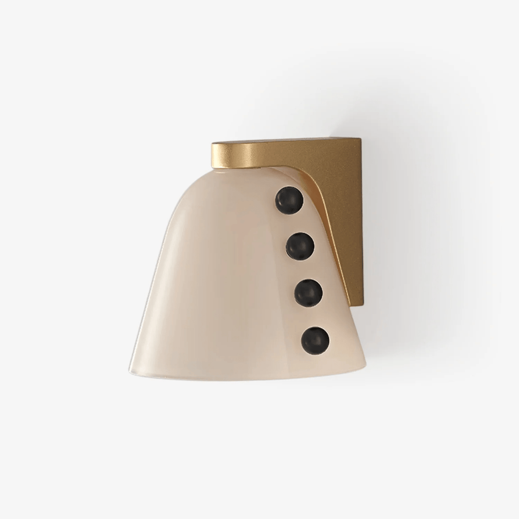 Wall light with a cream glass shade, four black glass studs and a brushed gold back bracket, on a plain white wall; a Clérachic wall sconce.