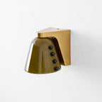 Close studio view of the olive-green glass shade, the gold bracket and four black studs, on white; a Clérachic wall light.