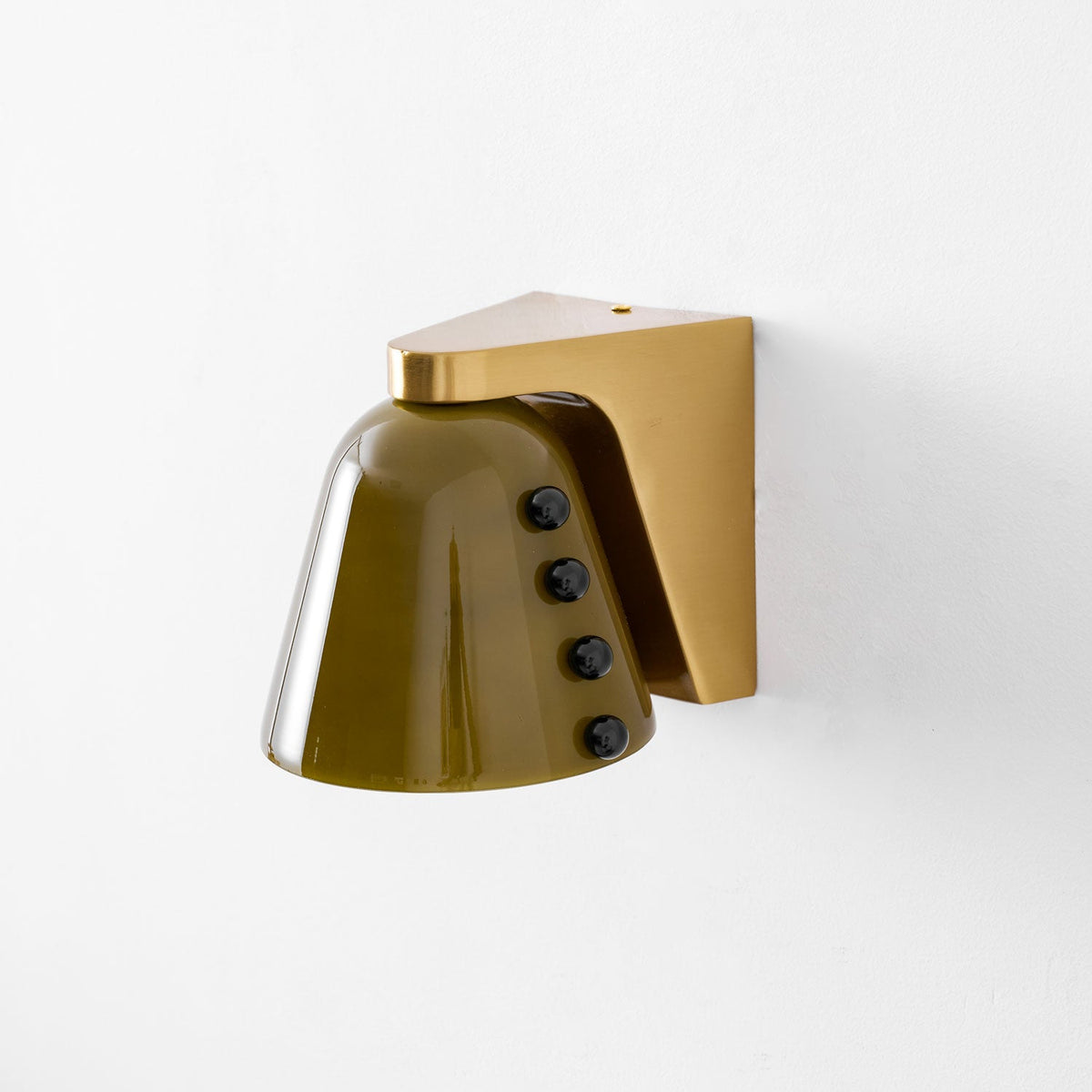 Close studio view of the olive-green glass shade, the gold bracket and four black studs, on white; a Clérachic wall light.