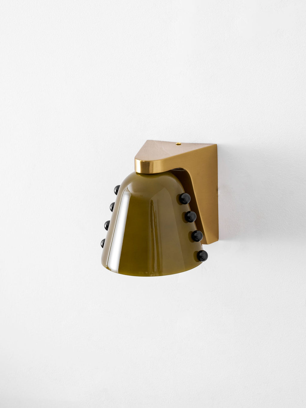 Green glass wall light with a gold bracket on a white wall, shown at a slight angle; a Clérachic design.
