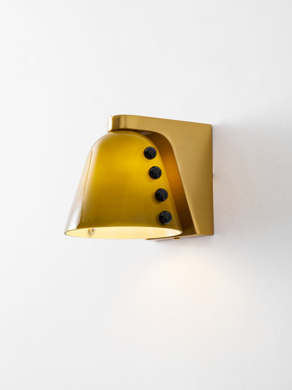 The lit green shade casts a warm pool of light below, seen from slightly beneath, with a gold bracket; a Clérachic wall light.