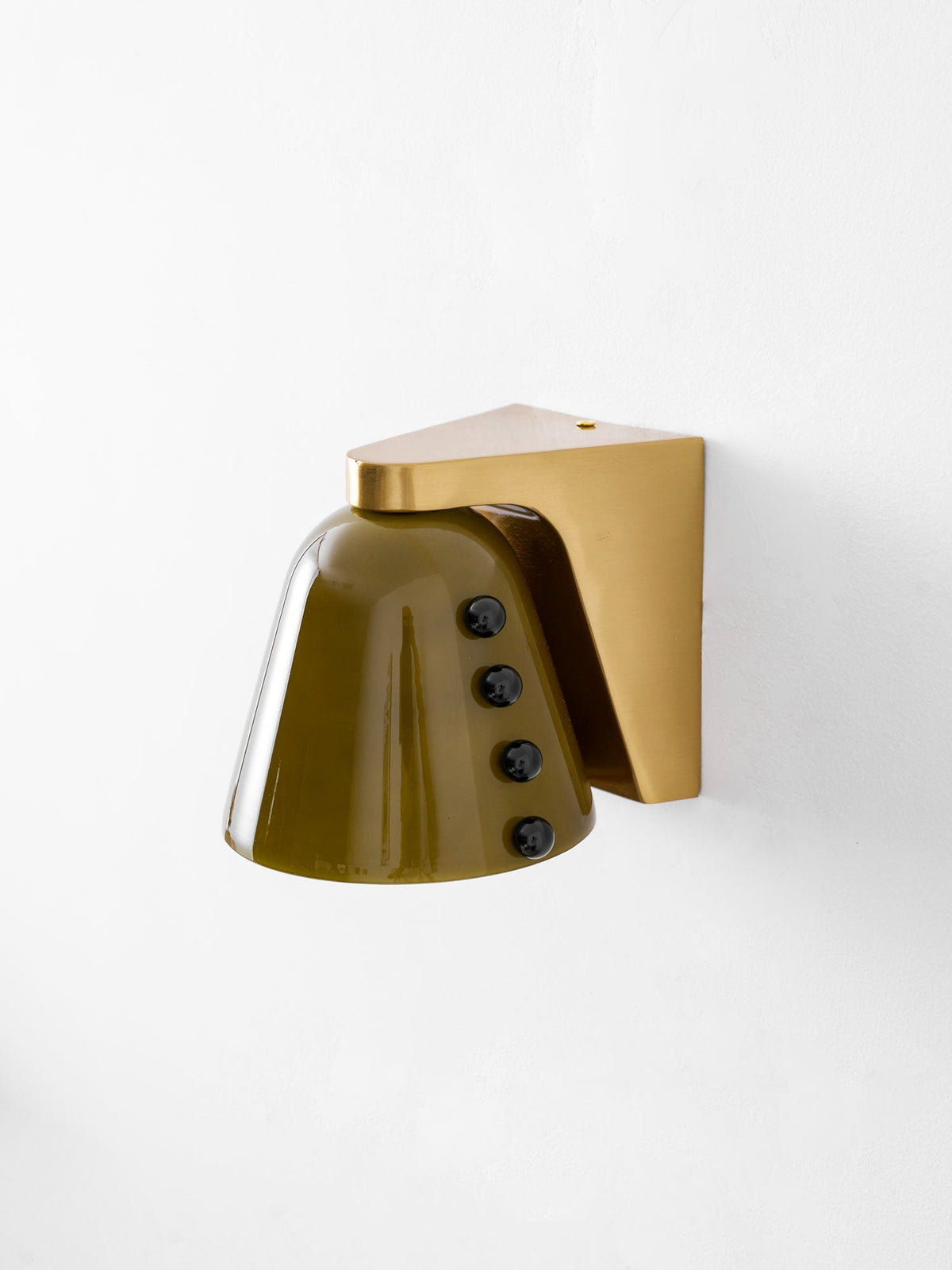 Three-quarter view of the green glass shade with its row of black studs, and a gold bracket at the top; from Clérachic.