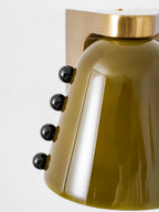 Close view of the green glass shade, the round gold cap and four black studs, cropped tight; this Clérachic wall light.