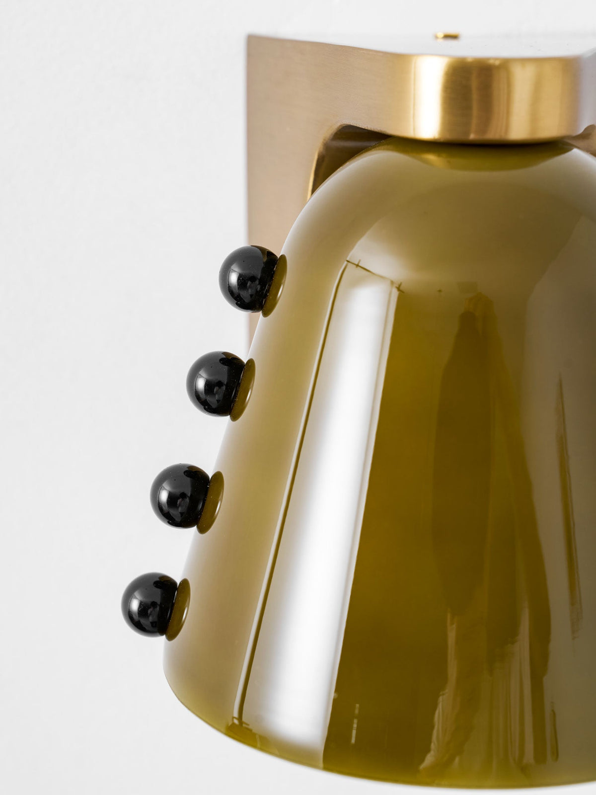 Close view of the green glass shade, the round gold cap and four black studs, cropped tight; this Clérachic wall light.