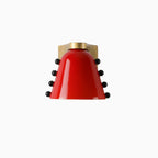 The red glass version of this Clérachic wall light, with black studs on both sides and a gold cap and bracket.