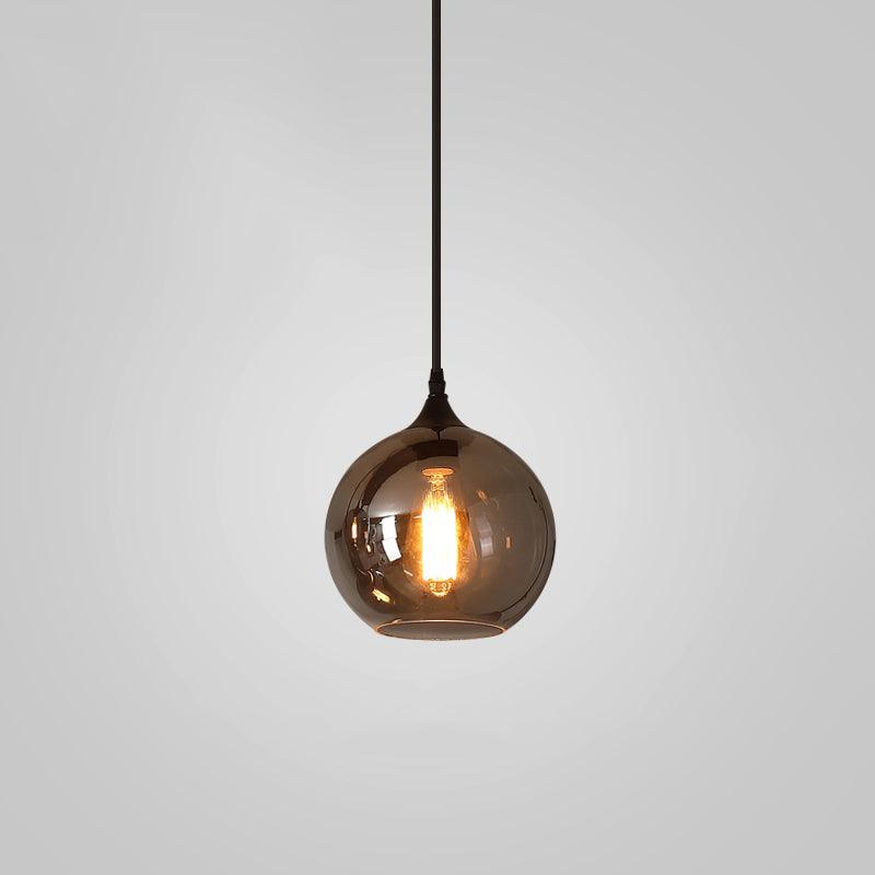 Round globe Clérachic smoked glass pendant, the bulb glowing amber through the mirrored tinted sphere.
